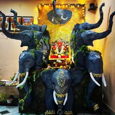 three elephants sitting on top of each other in front of a wall decorated with lights