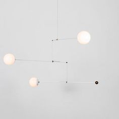 three light fixtures hanging from the ceiling in a room with white walls and flooring