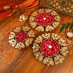 three metal bowls filled with pomegranates on top of a wooden table