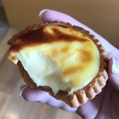 a hand holding a pastry with cream on it