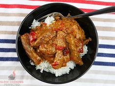 a black bowl filled with rice and meat on top of a striped table cloth next to a fork