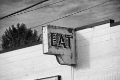 an old sign on the side of a building that says eat and is attached to a wall