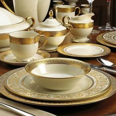 a table topped with white dishes and gold trimmings