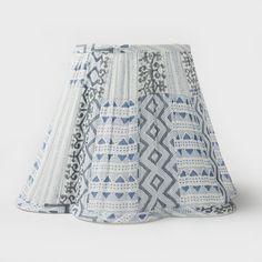 a blue and white lamp shade with geometric designs on the bottom, in front of a white background