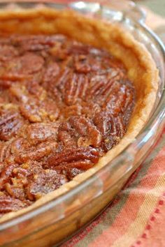 a pecan pie in a glass dish on top of a table with an orange towel