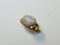 Beautiful ring made of rich 750 yellow gold with an orange red green yellow shimmering opal. A wonderful little natural spectacle! The stone is completely set in gold so that it is protected and the color is beautifully highlighted. The inside of the frame is blackened to give the play of colors more intensity. The ring band is made of oval for comfortable wearing. An absolute eye-catcher! I have more opals like this and can send you photos. Please just let us know. Dimensions Ring size: 55 or 1 Yellow Gold Ethiopian Opal Oval Cabochon Ring, Yellow Gold Ethiopian Opal Ring In Oval Cabochon Shape, Yellow Gold Ethiopian Opal Ring In Oval Shape, Ethiopian Opal Oval Cabochon Ring In Yellow Gold, Gold Ethiopian Opal Ring With Oval Cabochon, Gold Opal Ring Oval Cabochon, Gold Ethiopian Opal Oval Ring, Red Green Yellow, Beautiful Ring