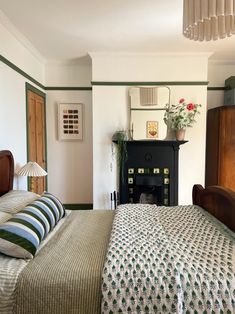 a bedroom with a bed, dresser and mirror in it's corner area next to a fireplace