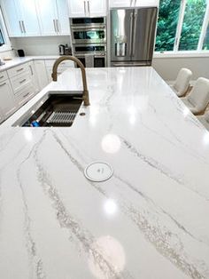 a large kitchen with white marble countertops and stainless steel appliances