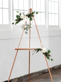 a wooden easel with flowers and greenery on it