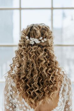 the back of a woman's head with curly hair and flowers in her hair