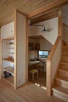 an open room with stairs leading up to a desk and bookshelf in the corner