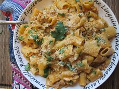 a white plate topped with pasta and meat covered in parmesan cheese, garnished with cilantro