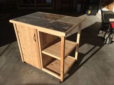 a small wooden table sitting on top of a cement floor next to a cart with wheels