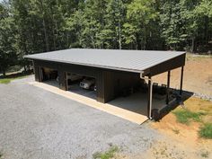 a garage with two cars parked in front of it and trees around the area behind it