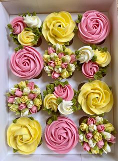 cupcakes in a box decorated with pink, yellow and white frosting flowers