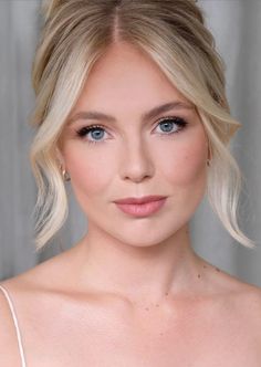 a woman with blonde hair and blue eyes wearing a white dress is looking at the camera