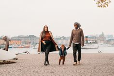 a man and woman holding hands while walking with a small child in front of them