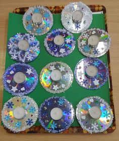 many different colored cds are arranged on a green surface with white candles in the middle