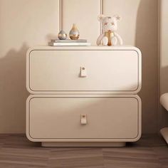 a white dresser with two drawers and a teddy bear on top