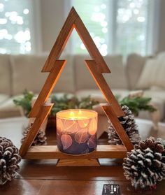 a candle sitting on top of a table next to pine cones