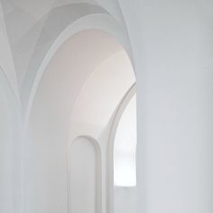 an empty hallway with white walls and arches