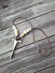 a necklace with a cross and beads on it sitting on a wooden table next to a bottle opener