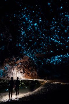 two people standing in front of a cave filled with blue lights