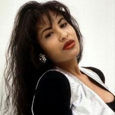 a woman with long dark hair and earrings on her head is posing for the camera