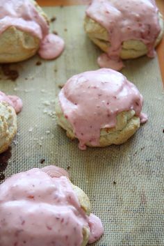 cookies with pink icing on a baking sheet