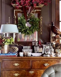 a christmas wreath is hanging on the wall above a dresser with wine glasses and other holiday decorations