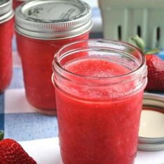 three jars filled with red liquid sitting on top of a blue and white checkered table cloth