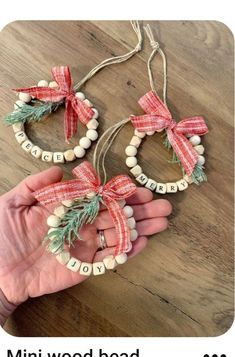 someone is holding two christmas wreaths made out of wood beads and twine string