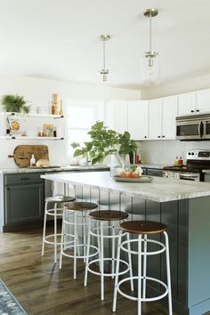 a kitchen with an island and bar stools next to the stove top oven in it