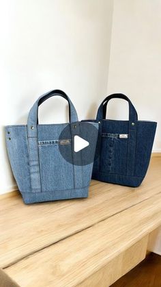 two denim bags sitting on top of a wooden table