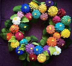 a wreath made out of crocheted flowers on a purple cloth with green leaves