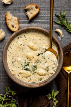 a wooden bowl filled with cheese sauce next to bread slices and garlic on a table