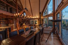 a living room filled with furniture and lots of windows next to a wooden dining table