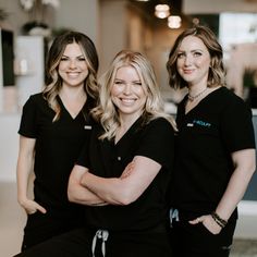 three women in black scrubs are smiling for the camera