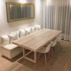 a table with white chairs and a bench in front of a mirror on the wall