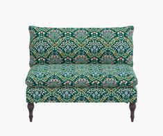 an upholstered couch with green and blue floral print on the back, sitting in front of a white background