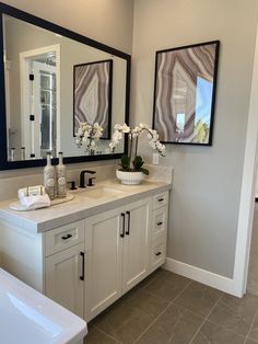 a bathroom with double sinks and two mirrors on the wall next to it's bathtub