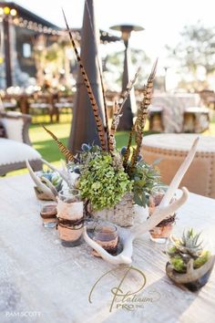 an outdoor table with plants and antlers on it