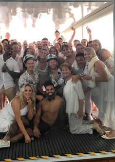 a large group of people are posing for a photo on the deck of a boat