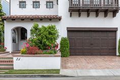 a white house with brown garage doors and flowers