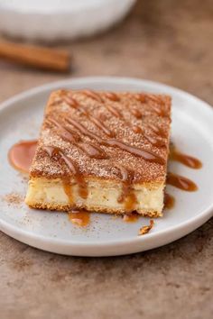 a piece of cheesecake on a white plate with caramel sauce drizzled over it