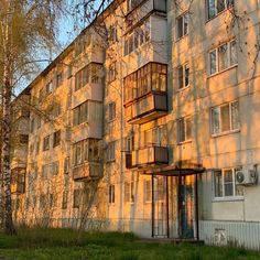 an apartment building with balconies on the side and trees in the foreground