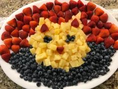 a white plate topped with fruit shaped like a hedgehog and surrounded by strawberries