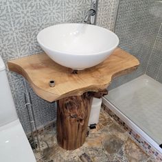 a white bowl sink sitting on top of a wooden stand