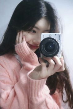 a young woman holding up a camera to take a selfie with her face close