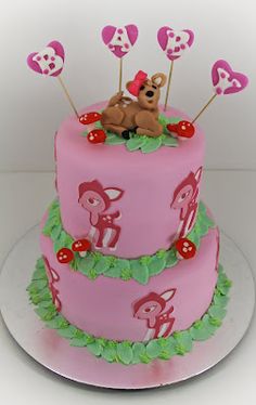 there is a pink cake with hearts on it and a teddy bear sitting on top